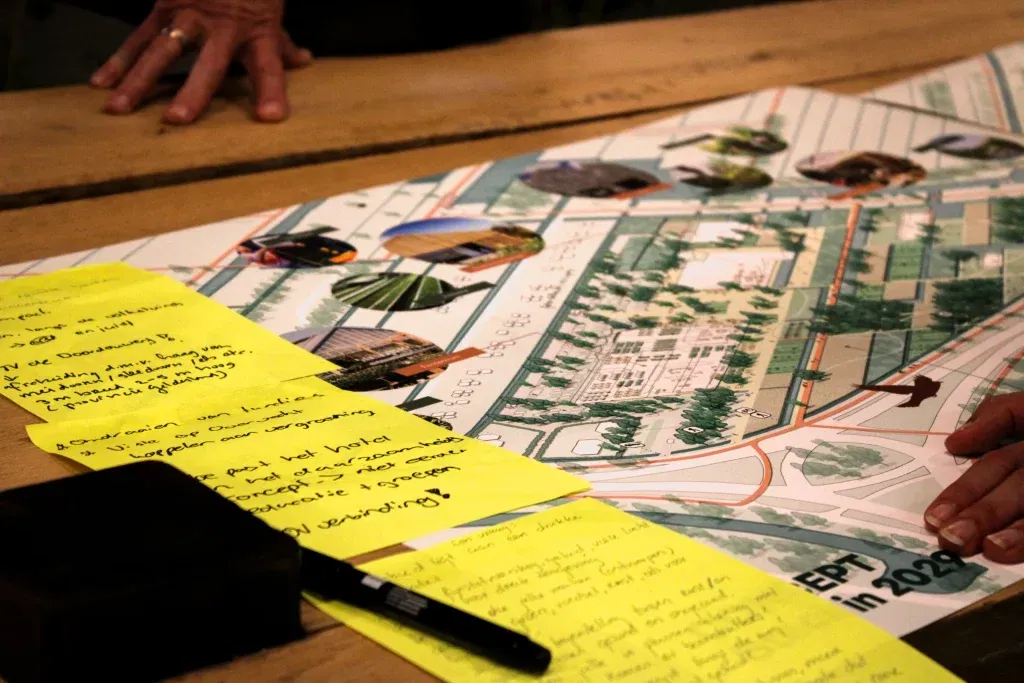 Op een tafel liggen visuele representaties van de toekomstplannen van Steck, met daarop briefjes waarop omwonenden hun zorgen, opmerkingen en tips hebben geschreven