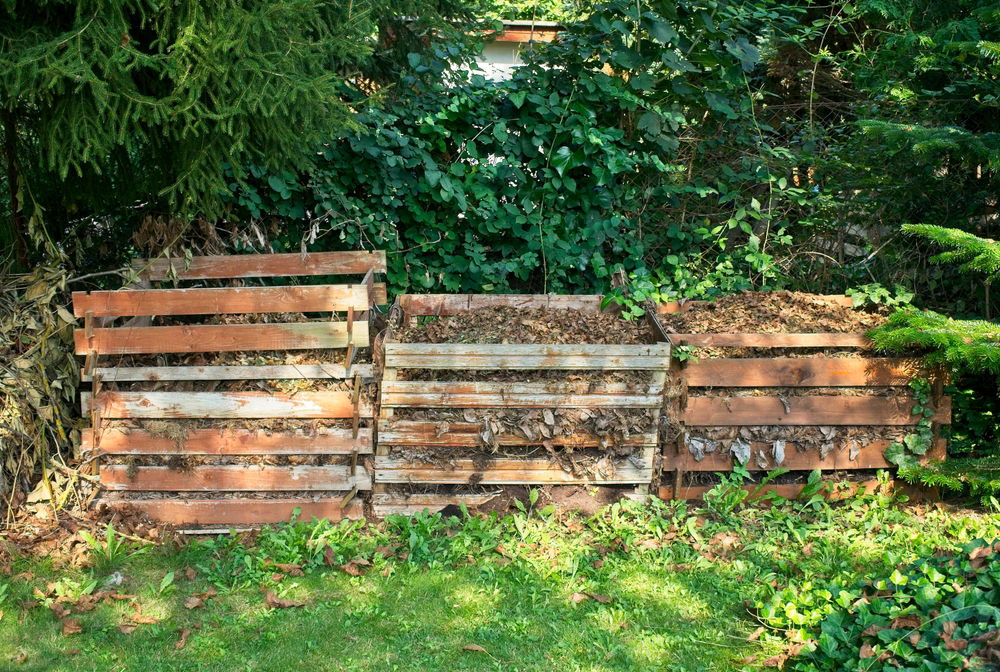 Drie open compostbakken op een rij