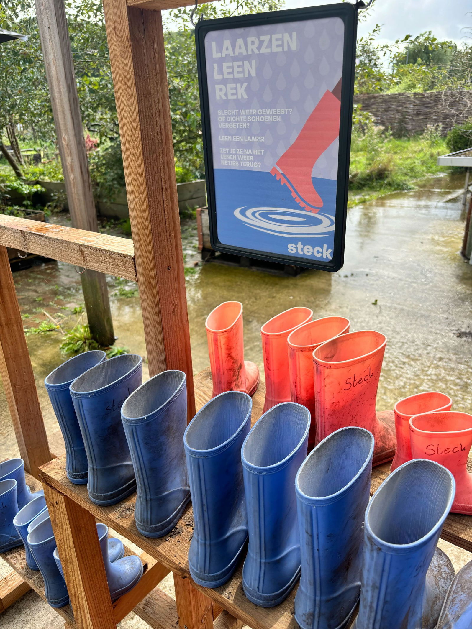Roze en blauwe kinderlaarsjes op een stellage, die gratis geleend kunnen worden die kinderen die het buitenterrein van Steck willen verkennen
