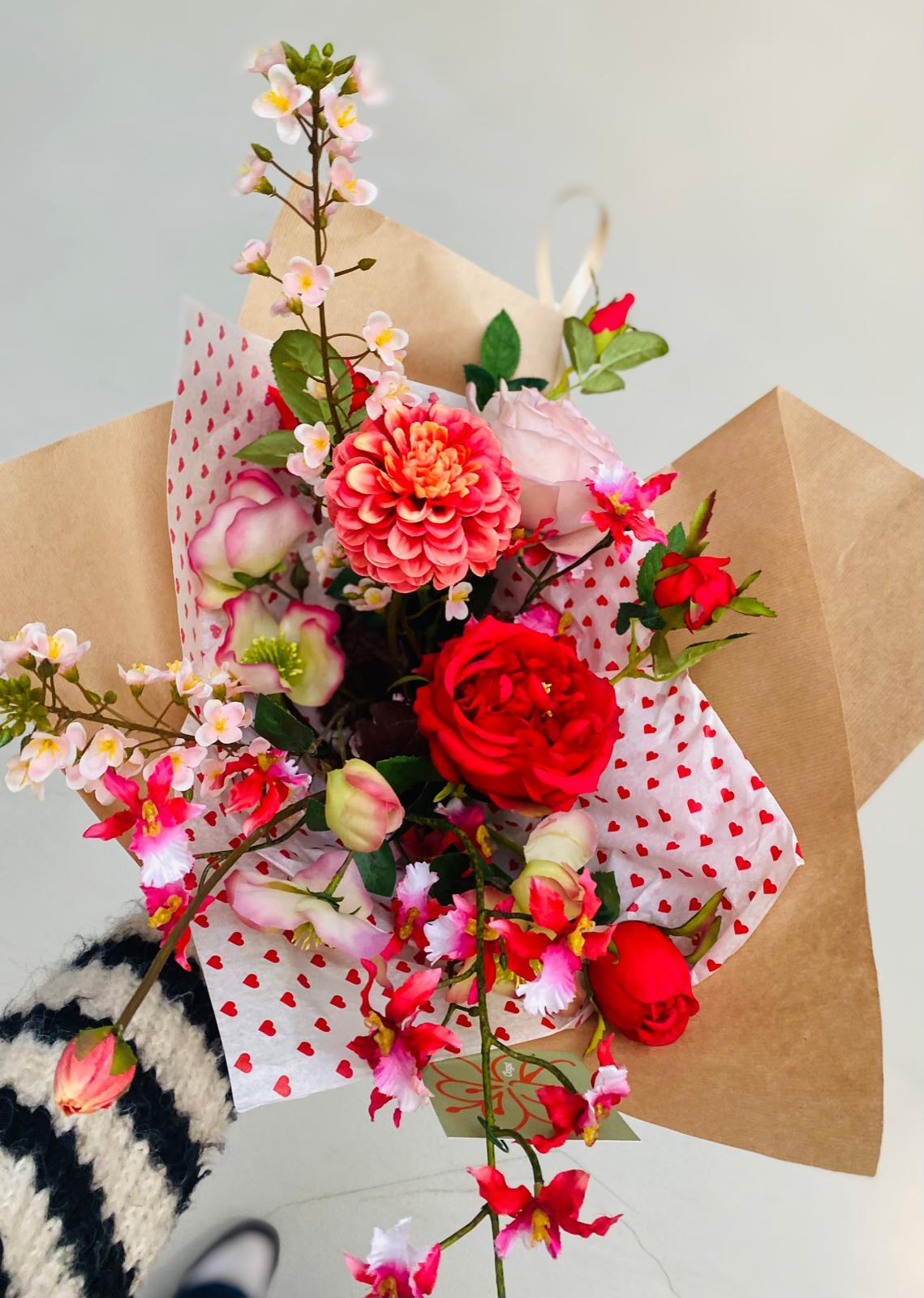 valentijns boeket met rode bloemen, vastgehouden door iemand met een zwart-witte trui