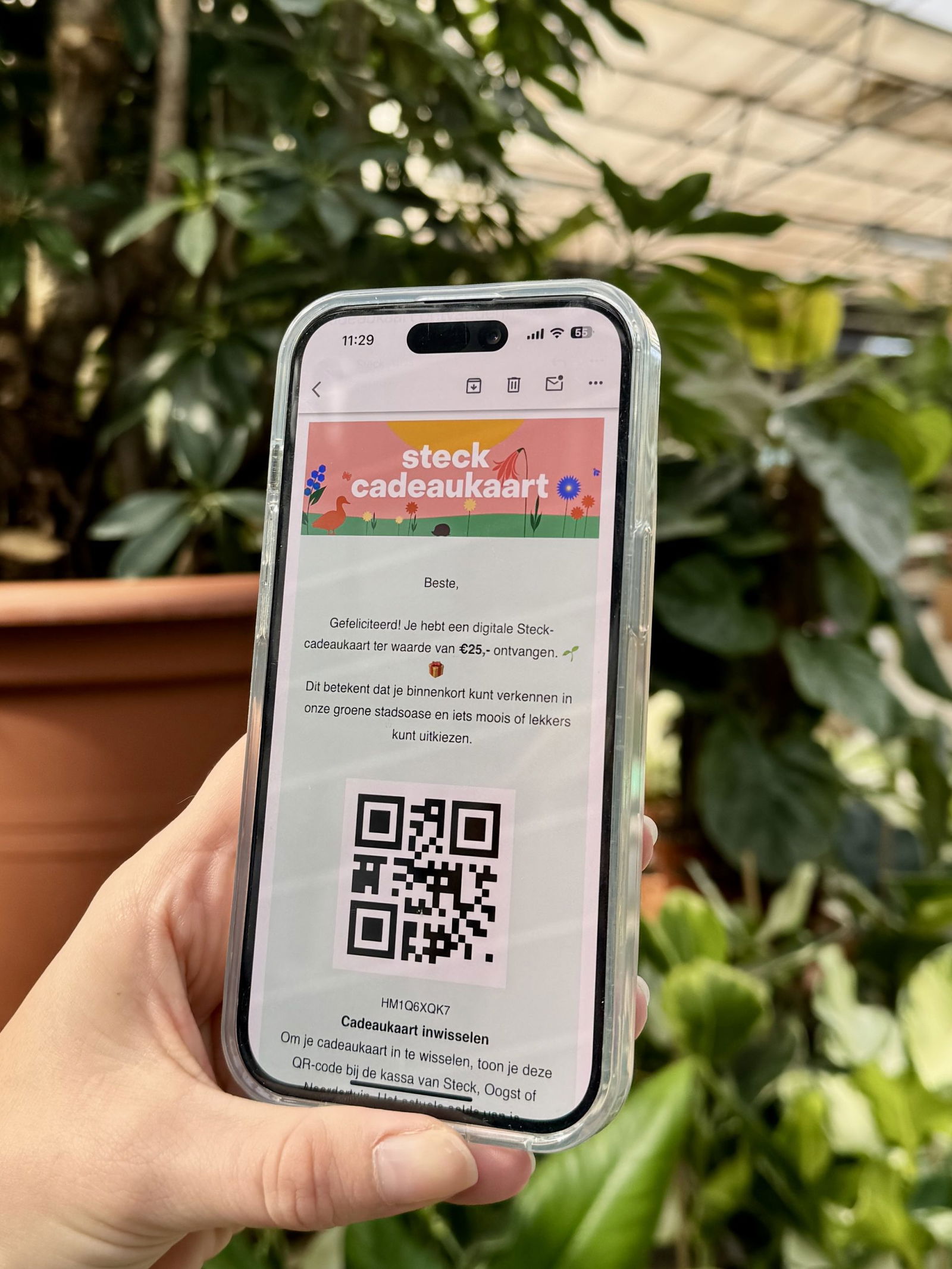 Een hand houdt een telefoon omhoog met daarop een digitale cadeaukaart van Steck.