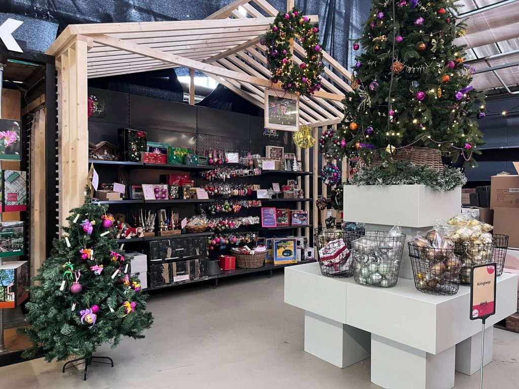 Het houten huisje van de Kerst Kringloopshop bij Steck, met kerstballen, kransen en een versierde kerstboom