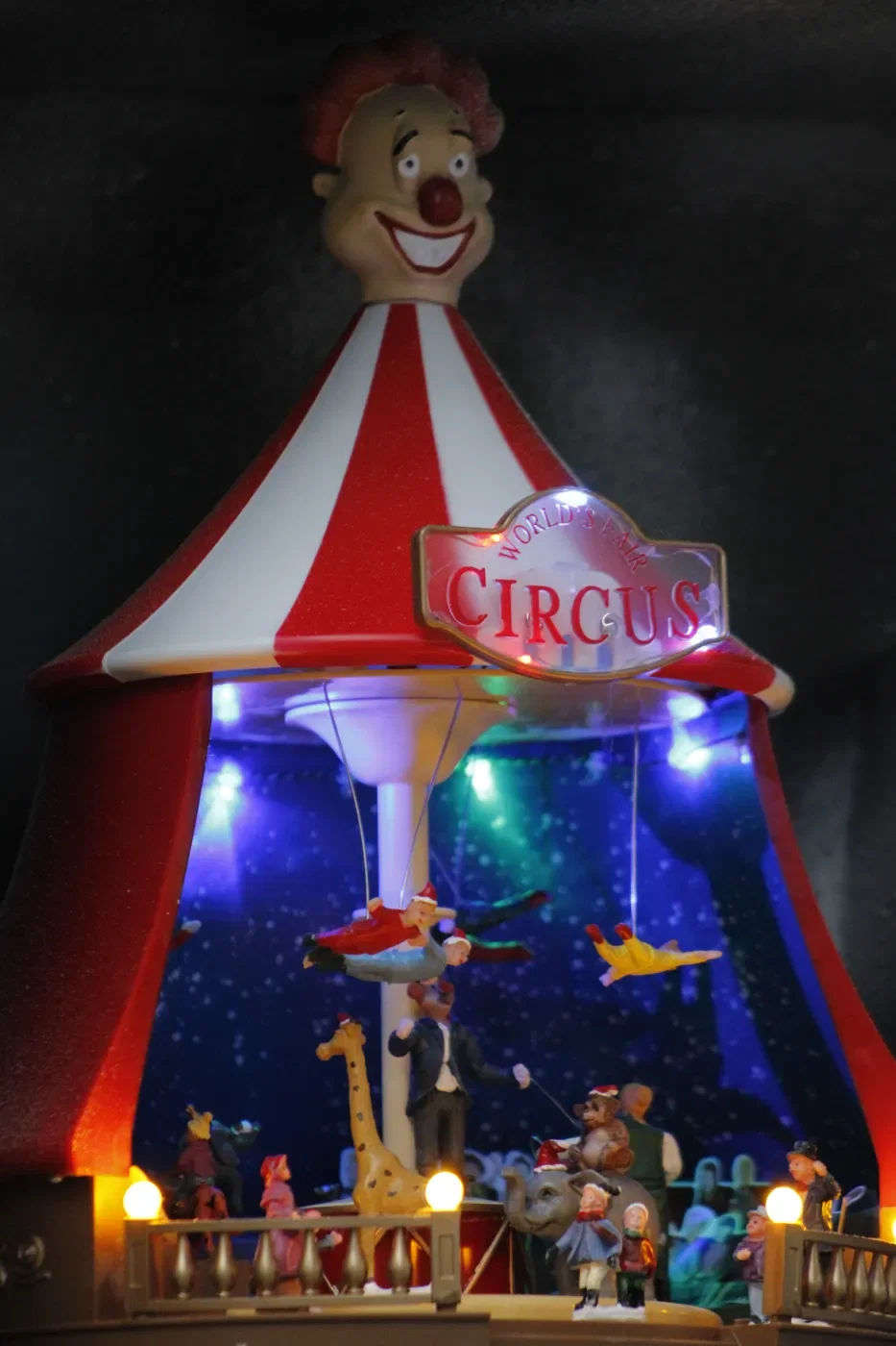 Verlicht kerstcircus met trapezewerkers en een clown op de nok